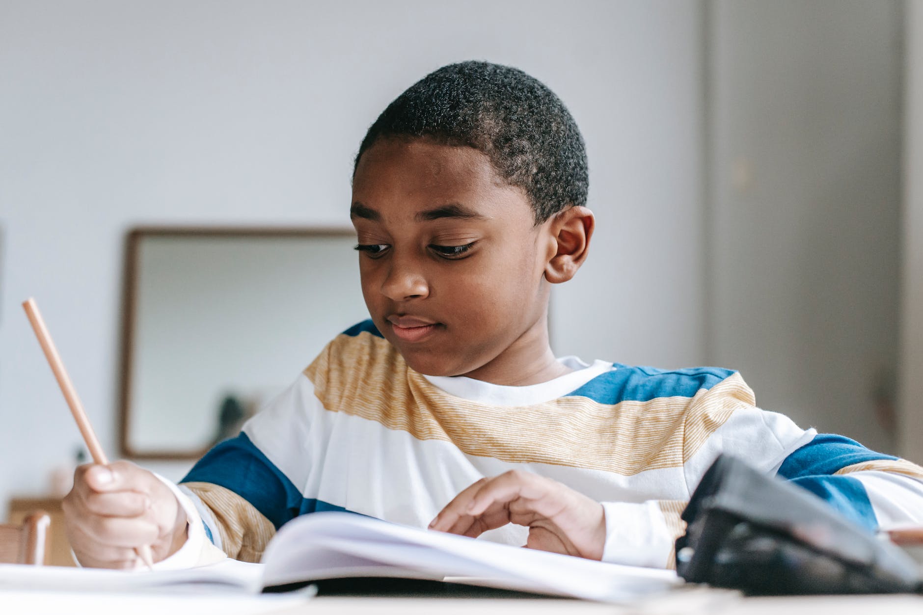 African American young boy writing in a workbook.