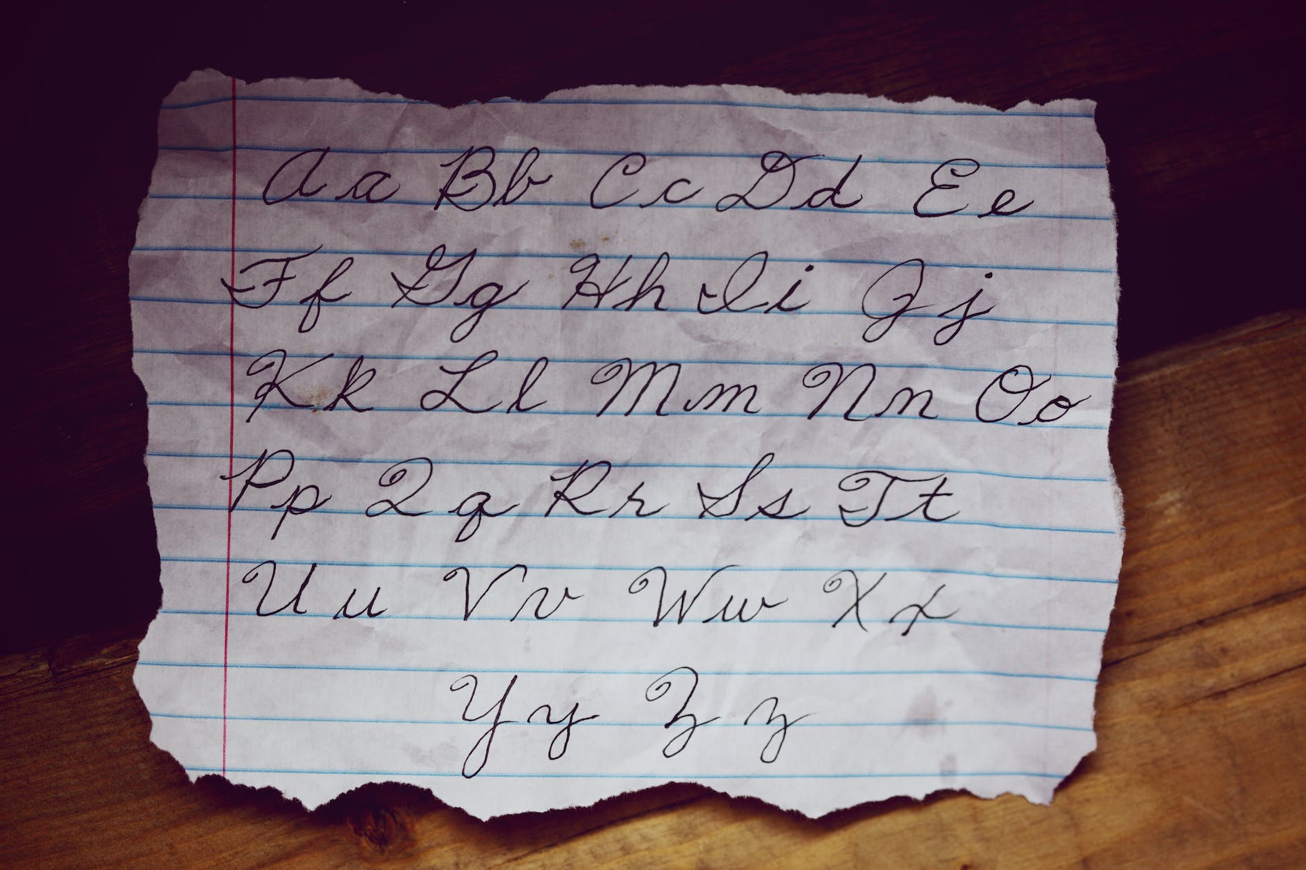 A rumpled piece of paper with the cursive alphabet on it