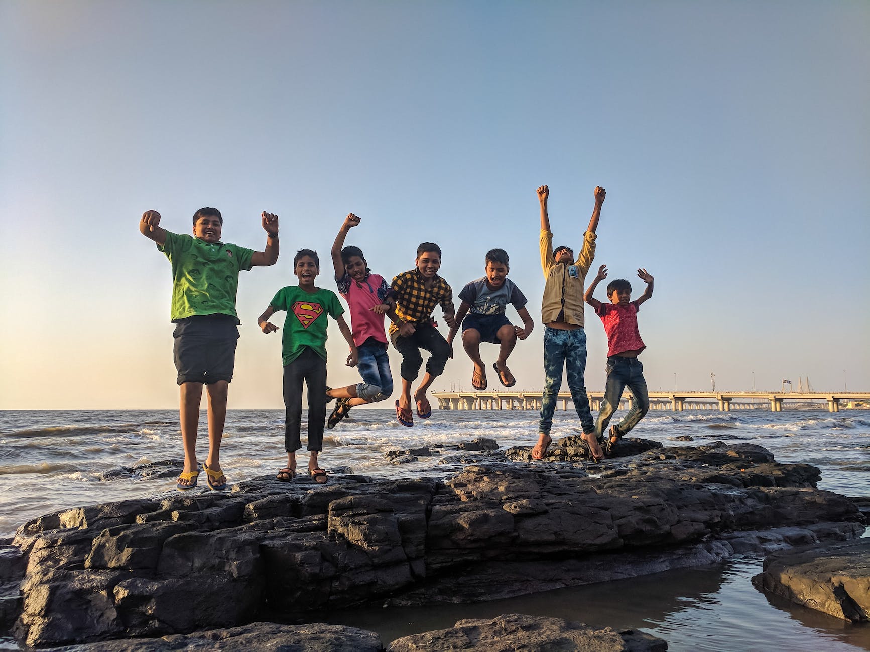 A line of kids jumping up at the beach