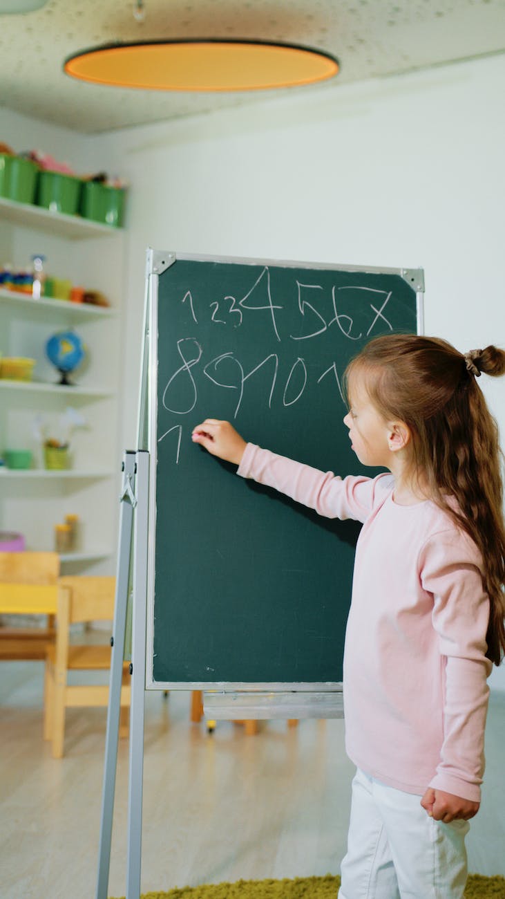 a kid writing numbers on a blackboard